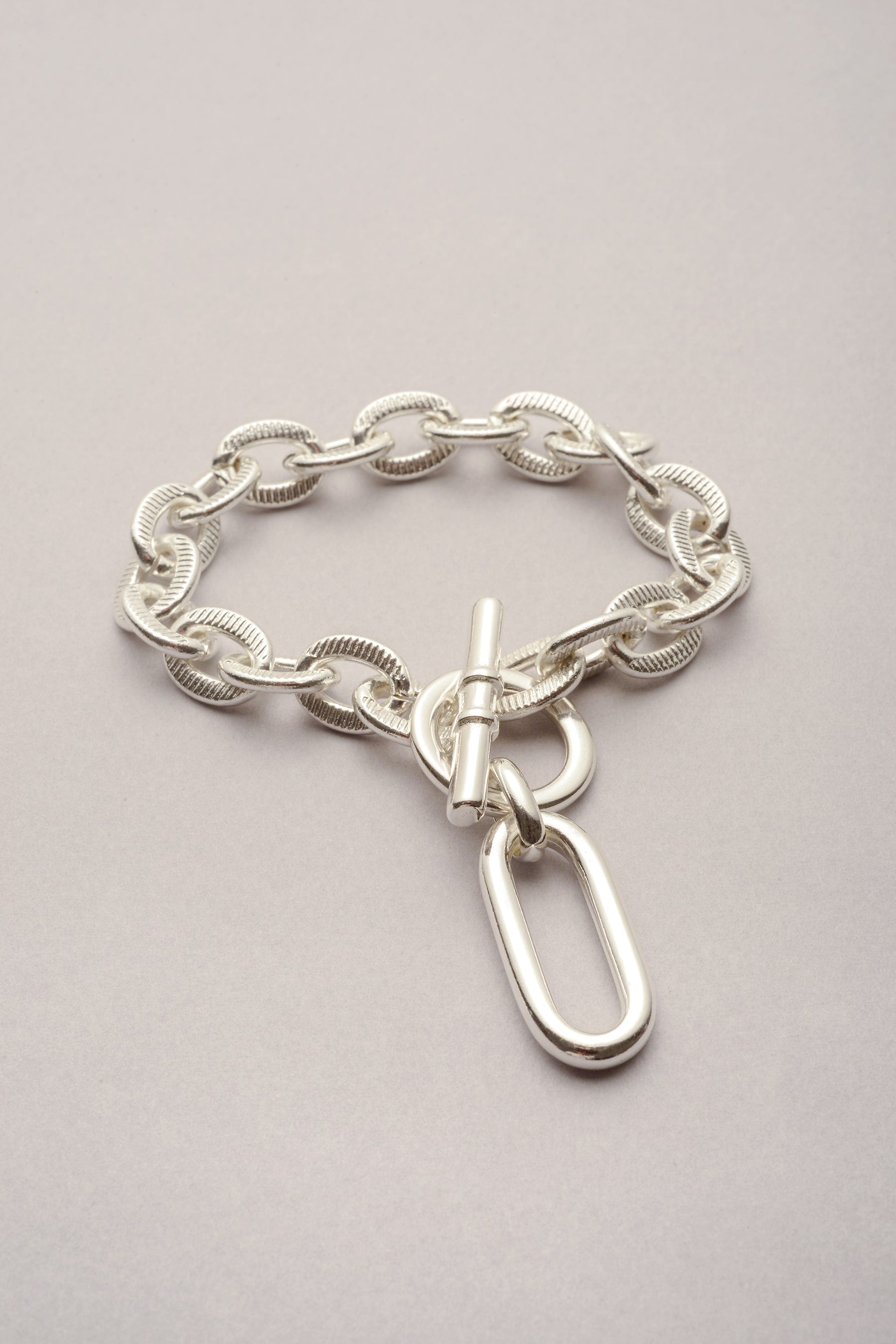 Bracelet Scarlett pendentif Ricky avec chaîne argentée. Ce bijou est fabriqué en France, et est composé d'un fermoir en T pour plus de praticité.