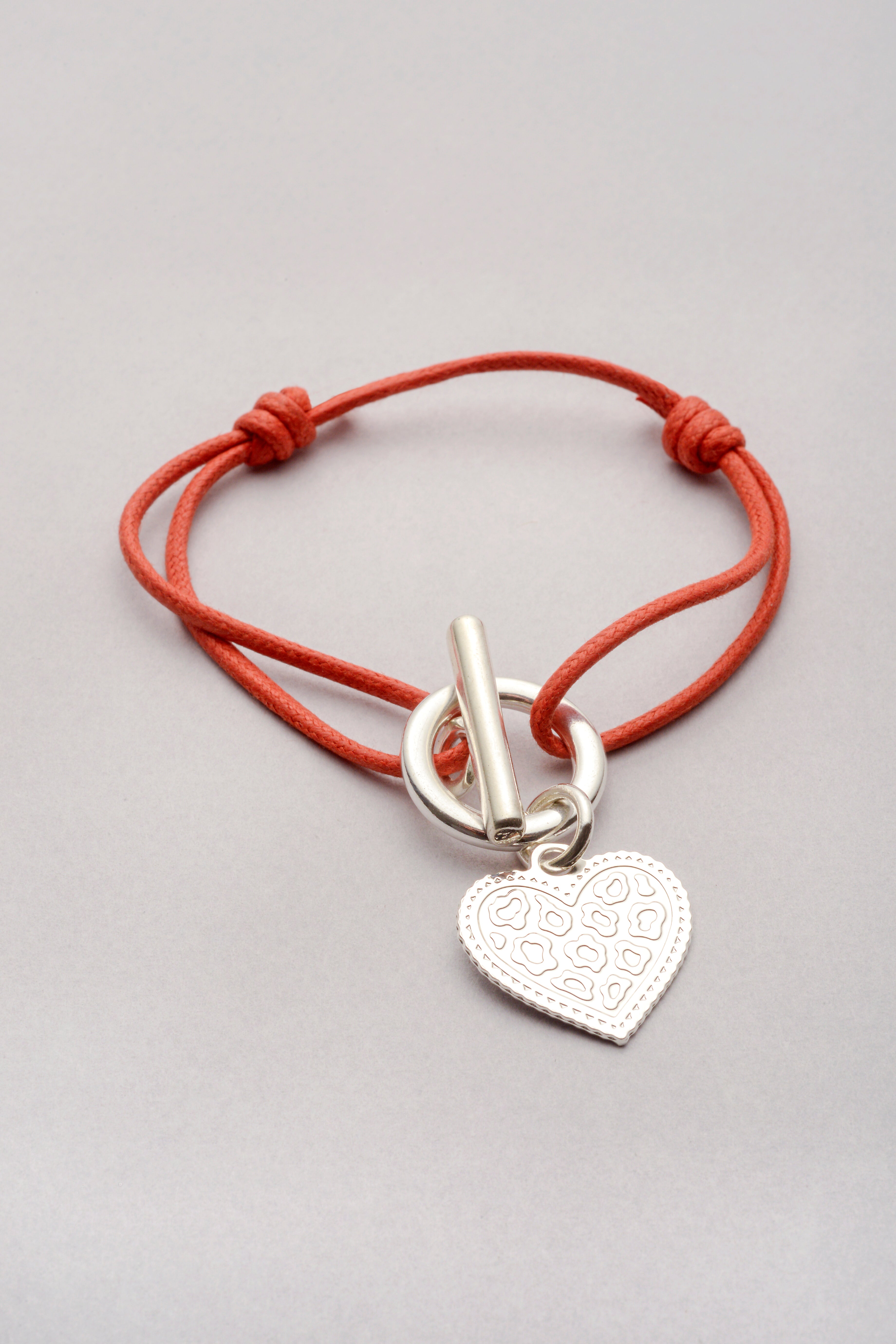 Bracelet argenté avec pendentif cœur motif léopard, monté sur un cordon réglable avec attache.