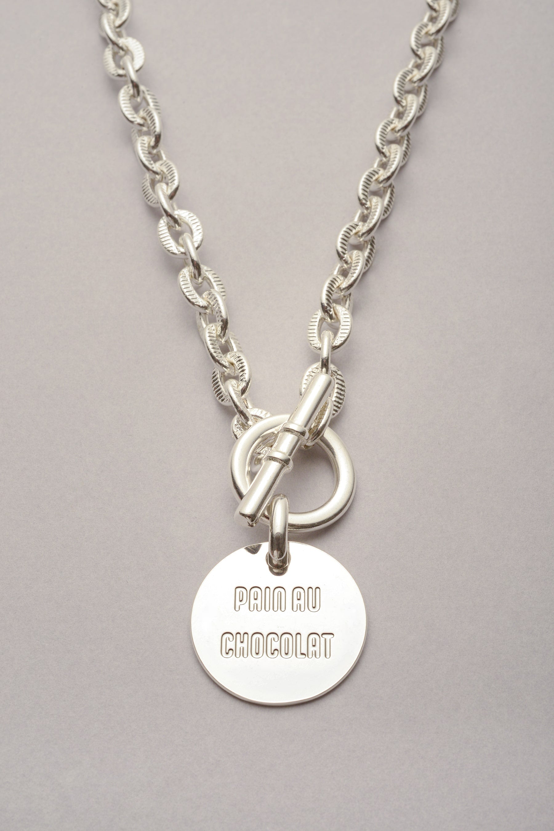 Le Collier Scarlett Médaille Pain au Chocolat est argenté et Fabriqué en France. Ce collier se compose d'un fermoir en T et d'une médaille grave Pain Au Chocolat. 
