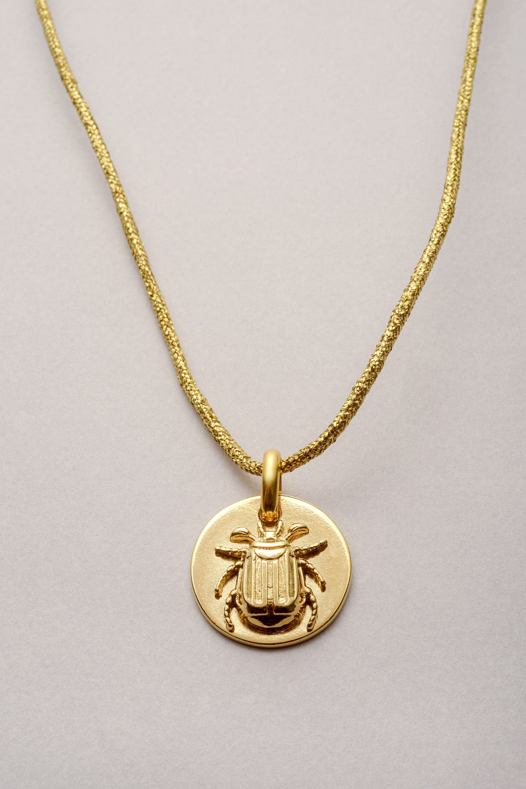 Ce bijou est composé d'un cordon de coton coloré et d'un pendentif scarabée doré. Le pendentif est une médaille avec un scarabée en relief : il a té soudé puis recouvert d'or dessus. 