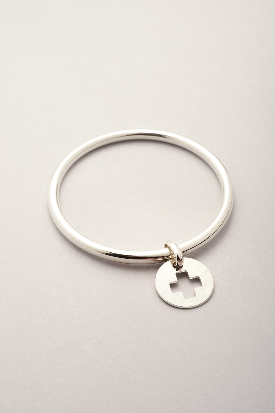 Ce jonc argenté est composé  d'un bracelet en forme de jonc argenté et d'une médaille avec une croix évidée. 