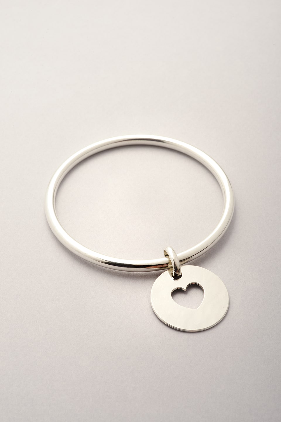 Ce jonc est constitué d'un bracelet argenté et d'une médaille avec un coeur évidé. Bijou fantaisie argenté pour femme. 