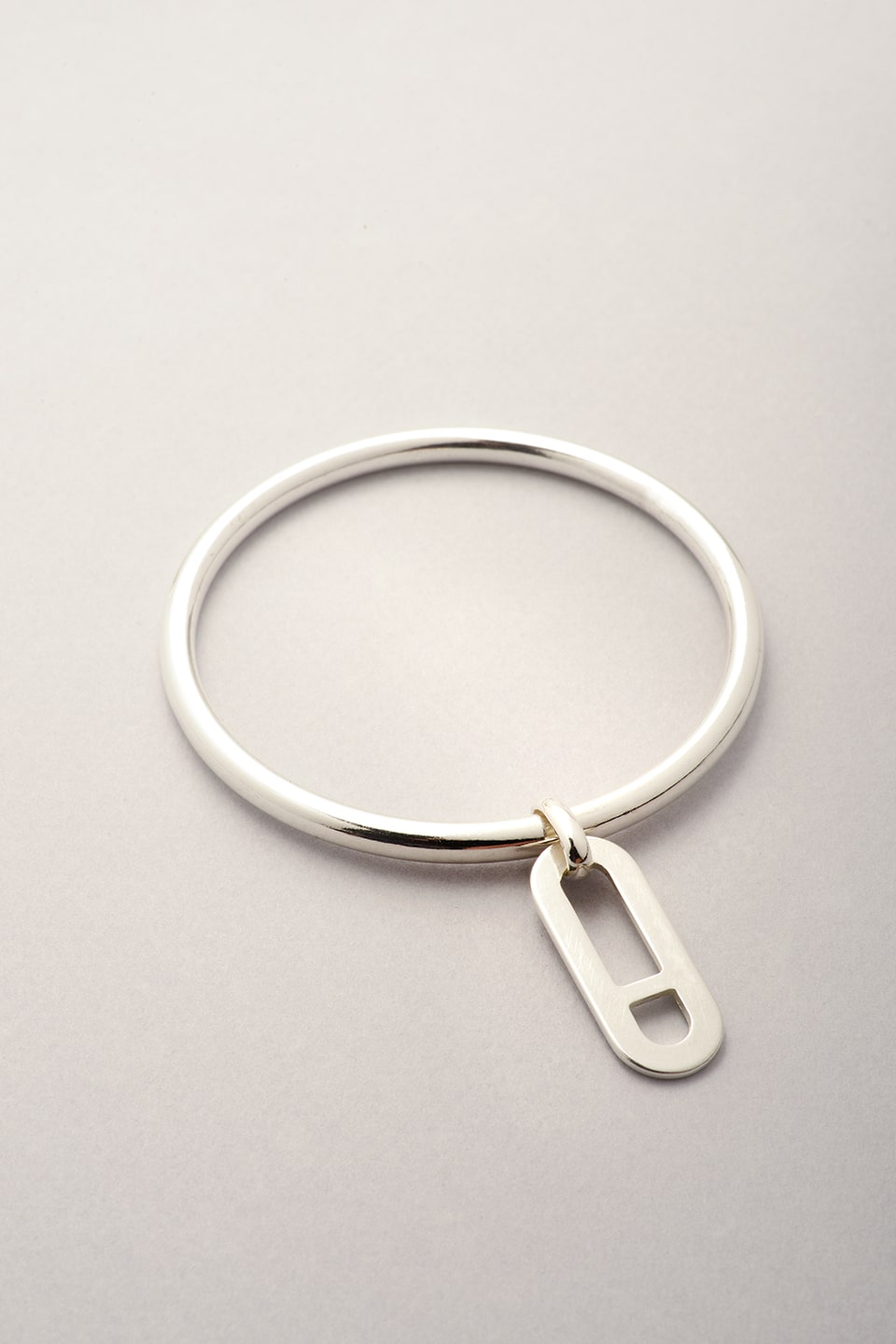 Ce bracelet jonc argenté est une création Musardise. inspiré de la maille Marine, ce pendentif est en forme ovale avec une barre à l'intérieur positionnée de manière symétrique. 