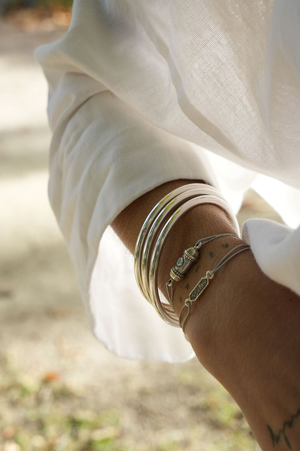 Bracelet Amal argenté porté en accumulation avec des joncs