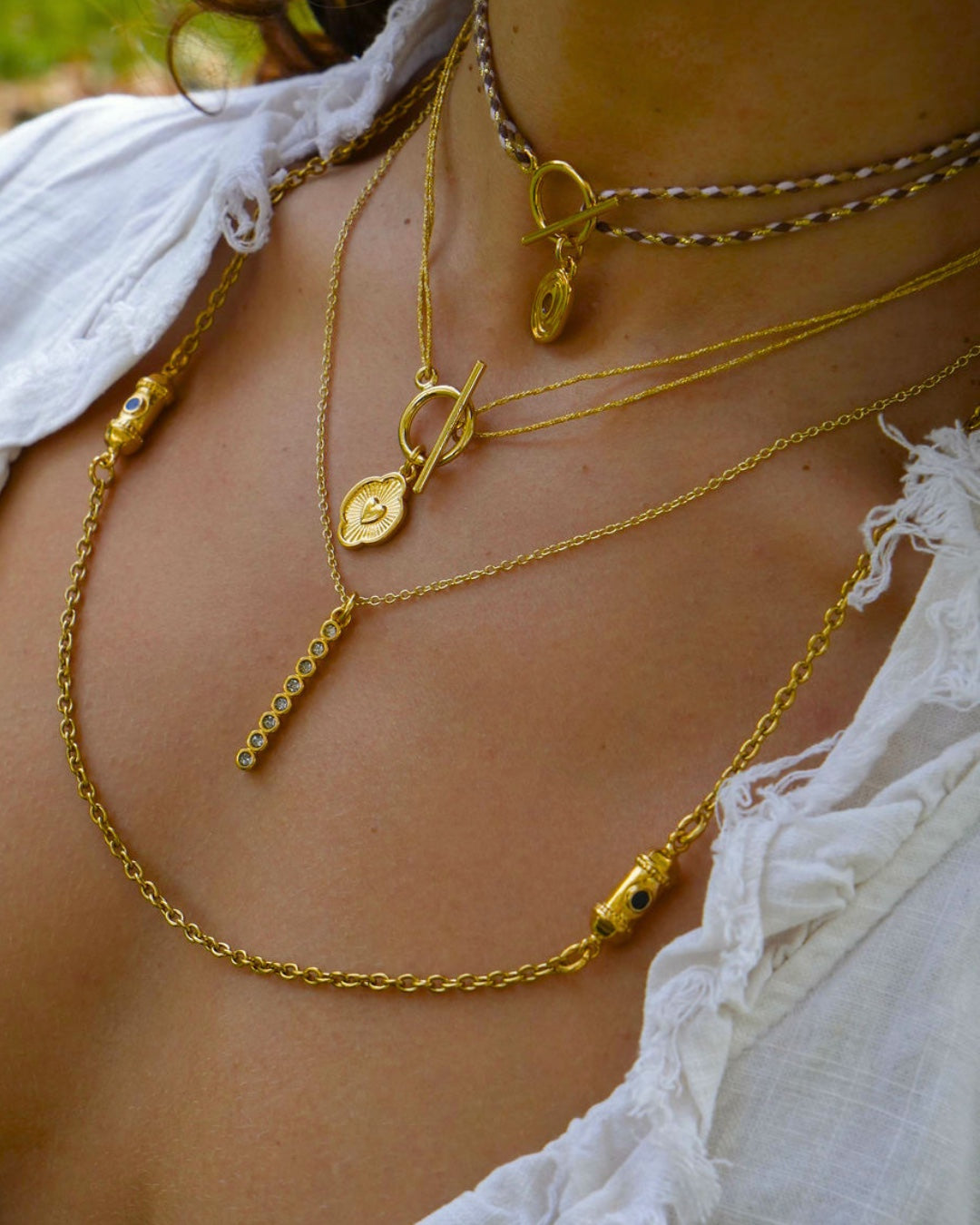 Collier chaîne dorée Strass porté en accumulation, pendentif barre à strass