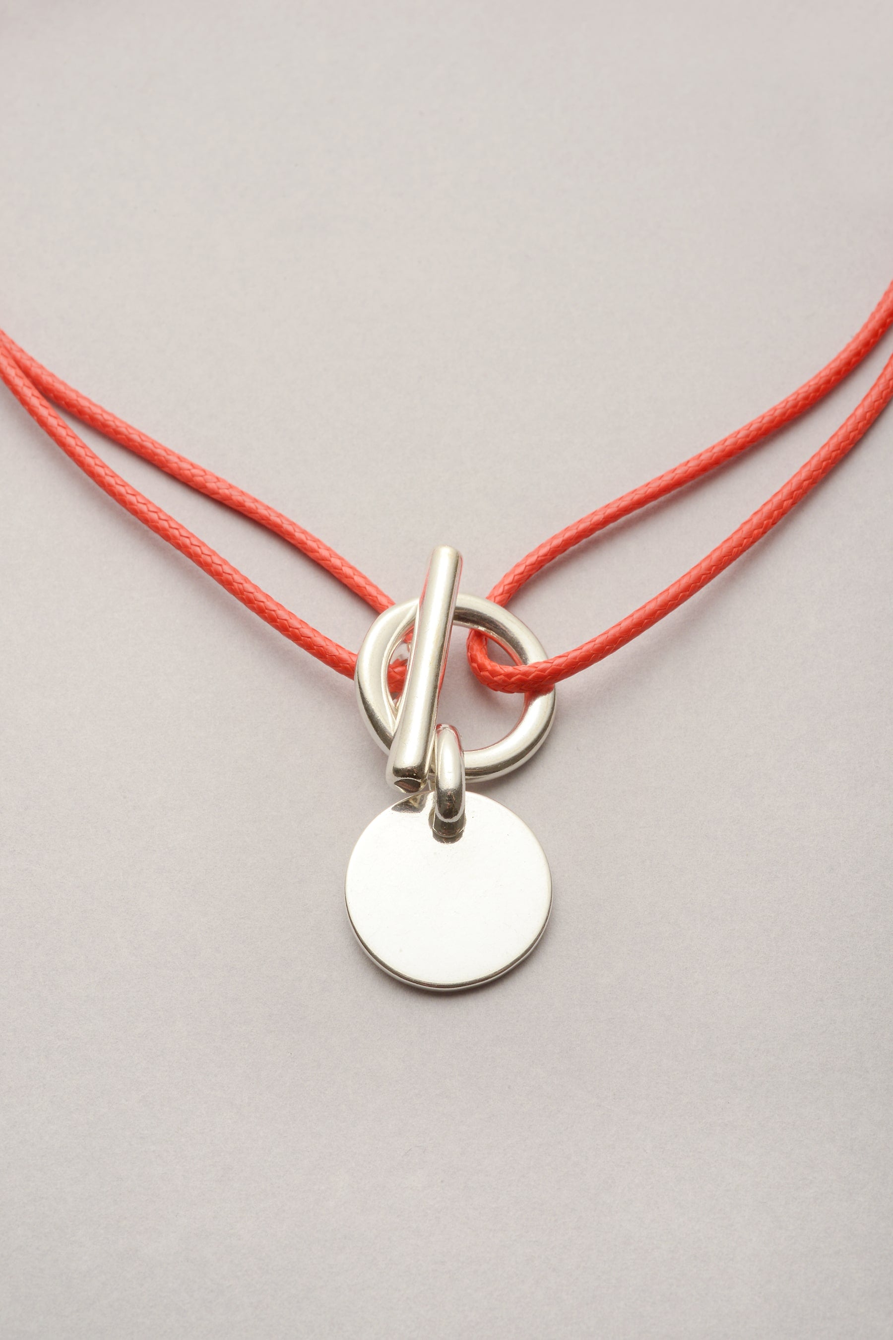 Ce collier est composé d'un cordon de coton coloré et d'un pendentif médaille 20mm. Ce bijou "attache" s'ouvre et se ferme grâce à son fermoir en T pour être pratique au quotidien. 